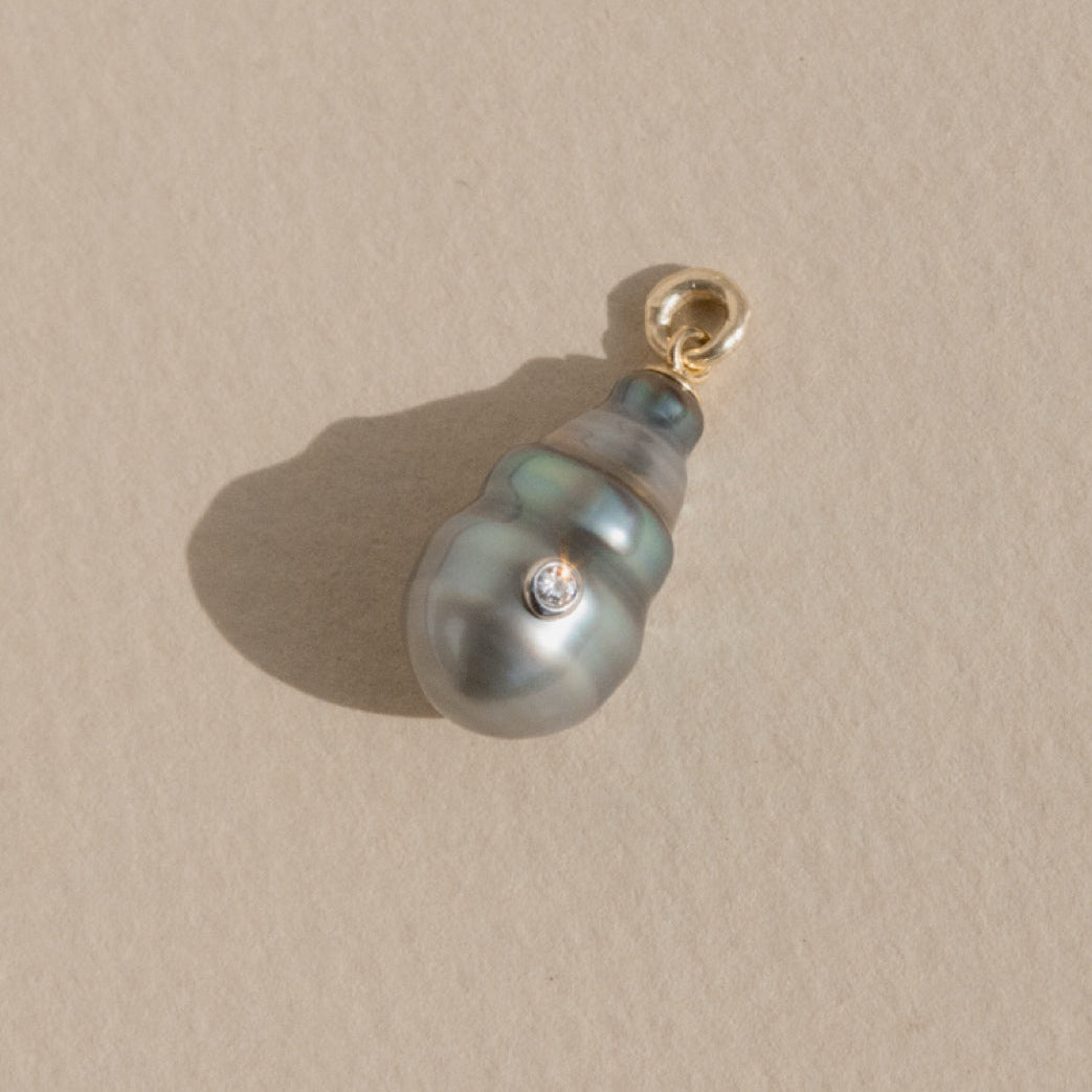 Pearl pendant with gold clasp on a beige background