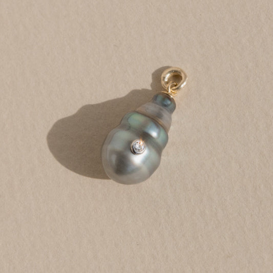 Pearl pendant with gold clasp on a beige background